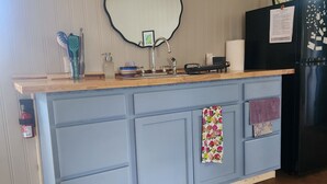 A kitchen with a wooden countertop, a sink, a black refrigerator, and a blue cabinet. - 1-bedroom, dog friendly cottage (Hot Springs)