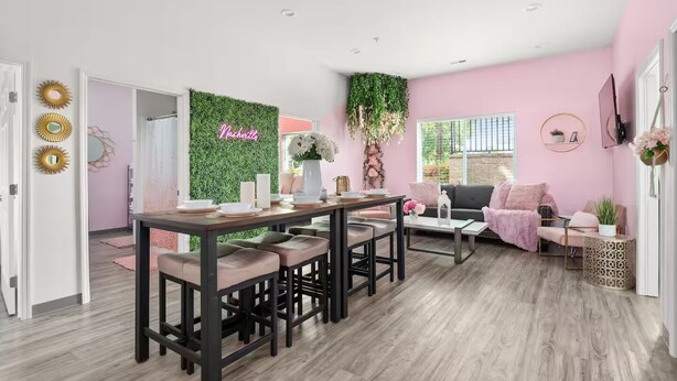 Een moderne woonkamer met een eetgedeelte, met een groene wand waarop 'Nashville' staat, een zithoek en een salontafel.