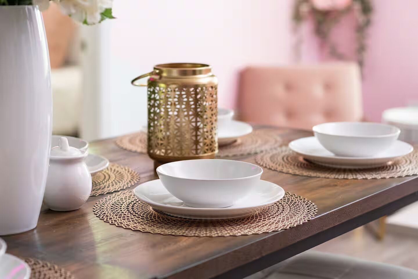 A dining table with white bowls and plates, a white pitcher, and a gold lantern.
