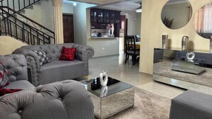 Una sala de estar con un sofá gris, una mesa de centro y una escalera.