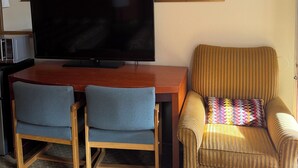 A living room with a flat-screen TV, two chairs, a sofa, a framed floral painting, and a microwave. - Federal way Motel (Federal Way)