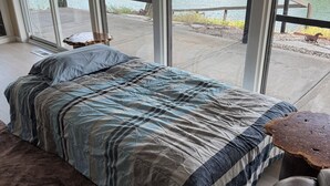 Ein Schlafzimmer mit einem großen Bett, Seeblick und einem rustikalen Holztisch.