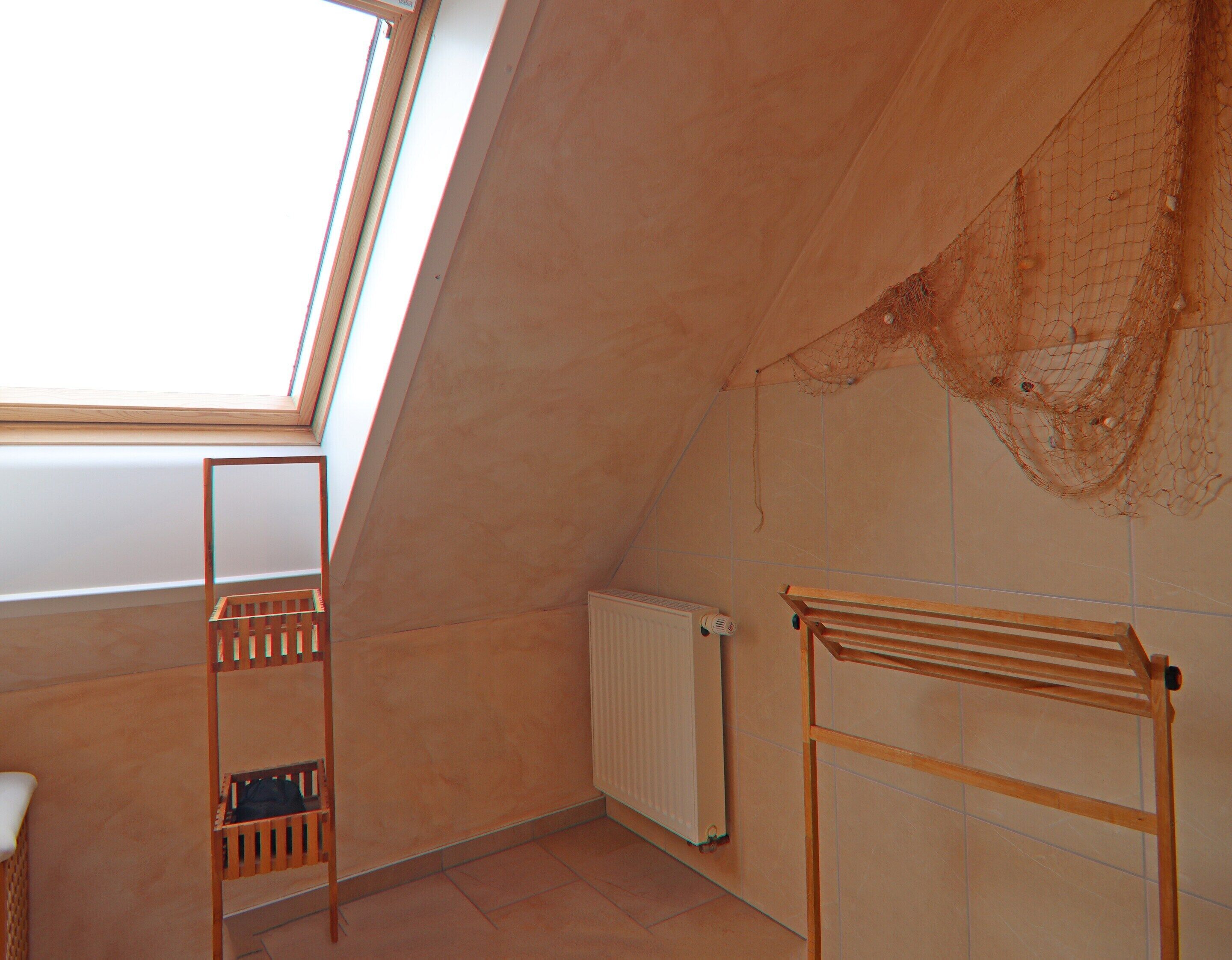 A sloped ceiling room with a skylight, a radiator, and wooden furniture.