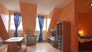A room with a sofa, a television, a cabinet, and a window with curtains. - Wunderschoene Ferienwohnung an der Mueritz (Röbel/Müritz)