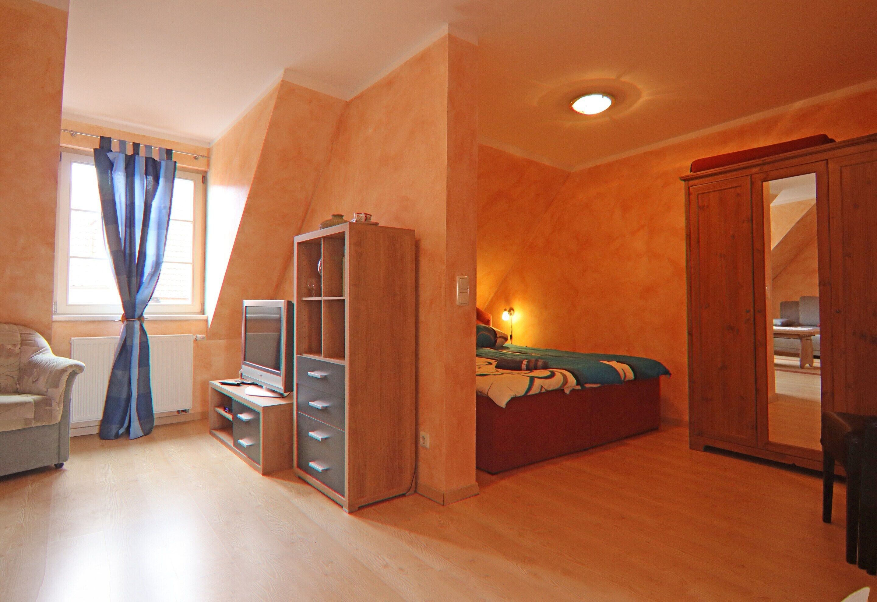 A bedroom with a bed, a TV, a wardrobe, and a chair.