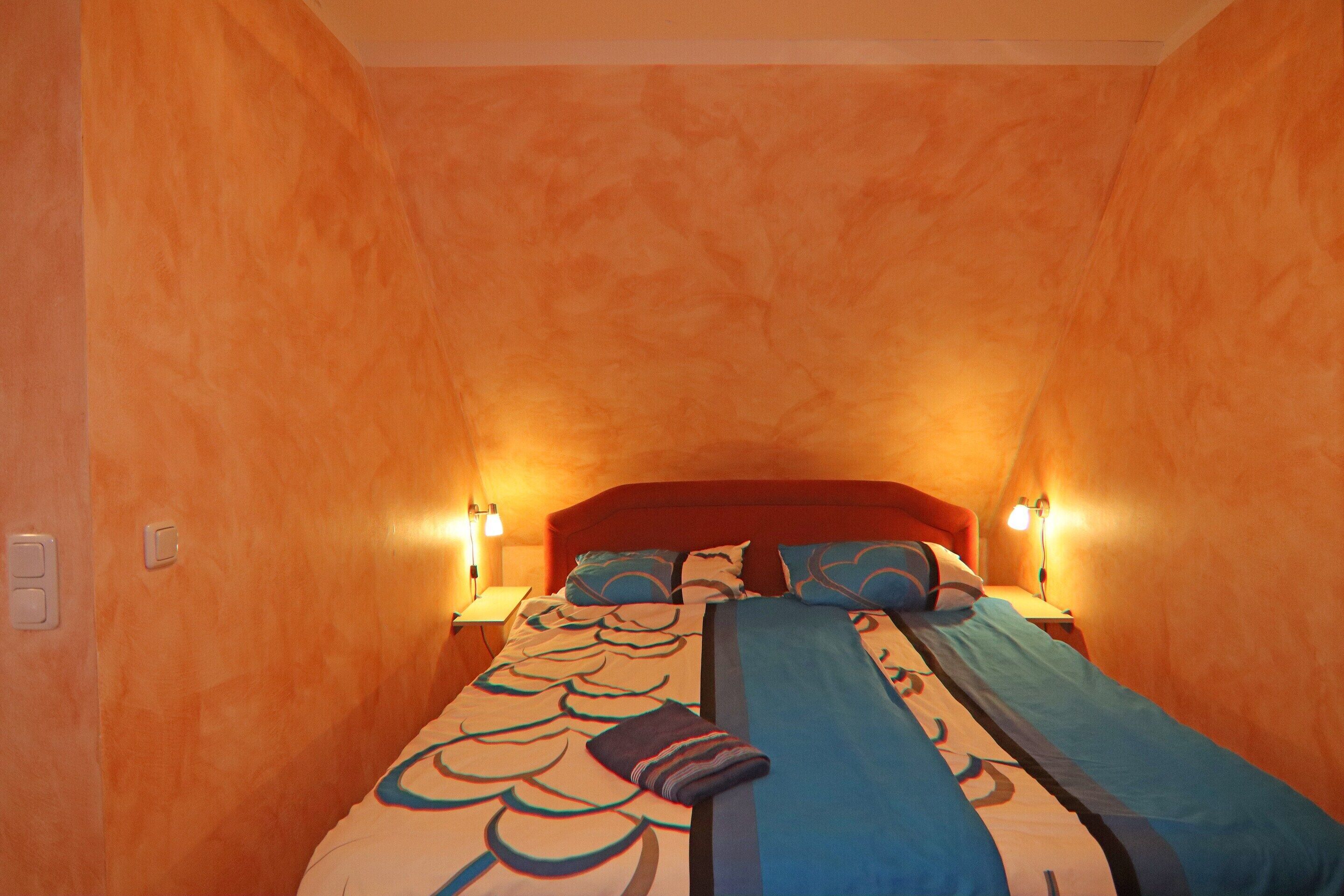 A bedroom with a bed, two bedside lamps, and a nightstand.
