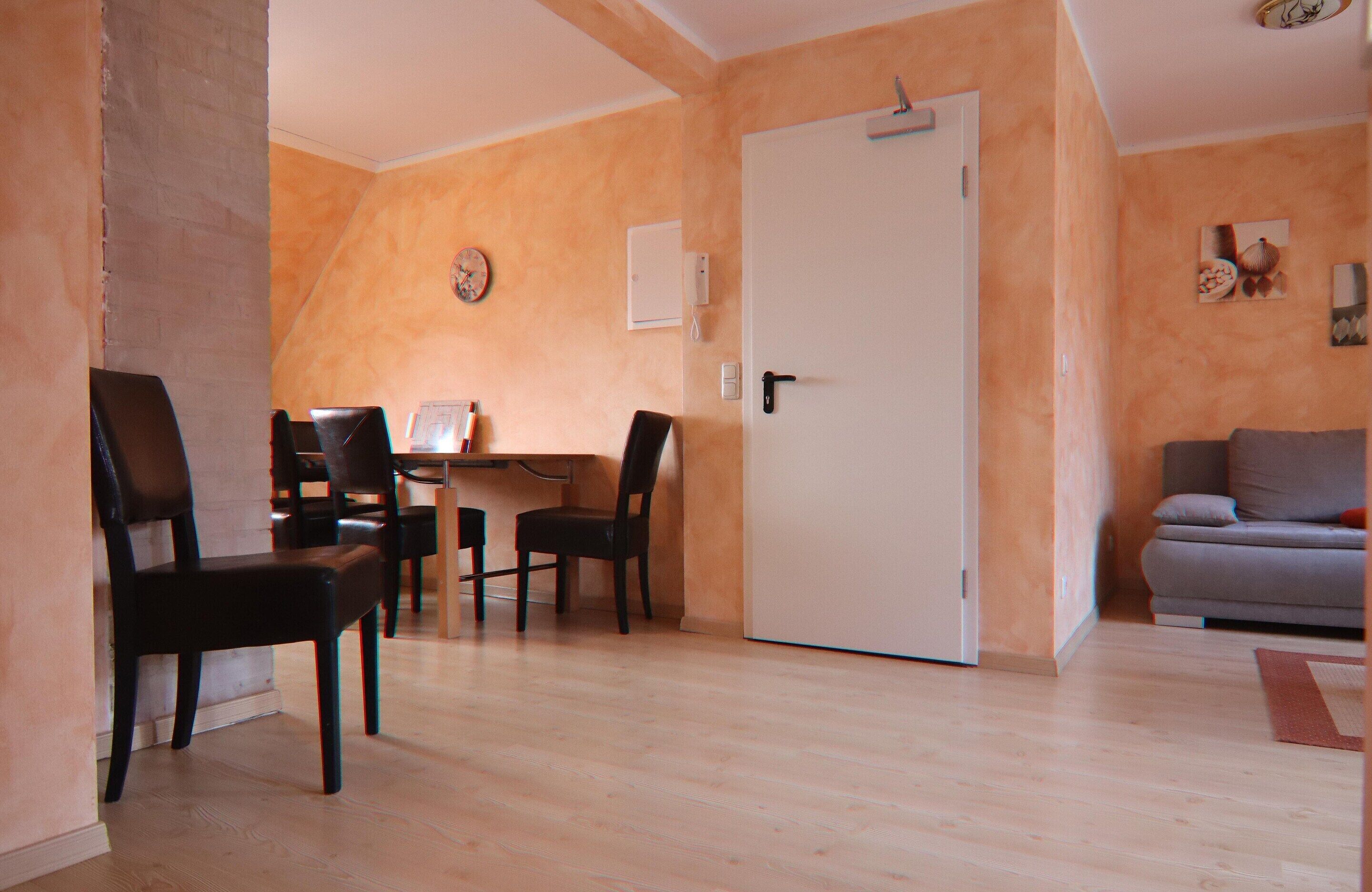 A living room with a sofa, a dining table with chairs, and a door.