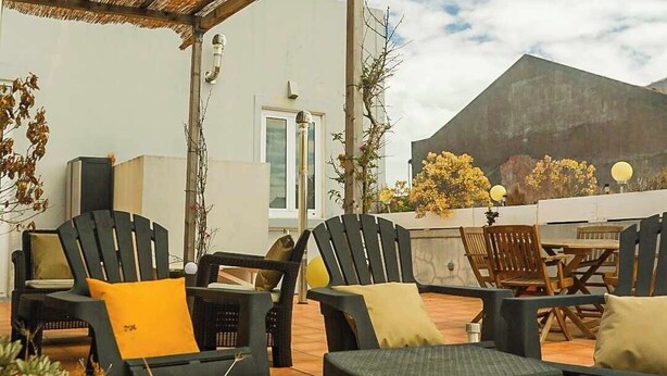 An outdoor patio with wicker furniture, terracotta planters, and a thatched roof structure. - Terrace bliss hot.Tub&city strolls ,5-10 m walk to restaurants and entertainment (Ponta Delgada)