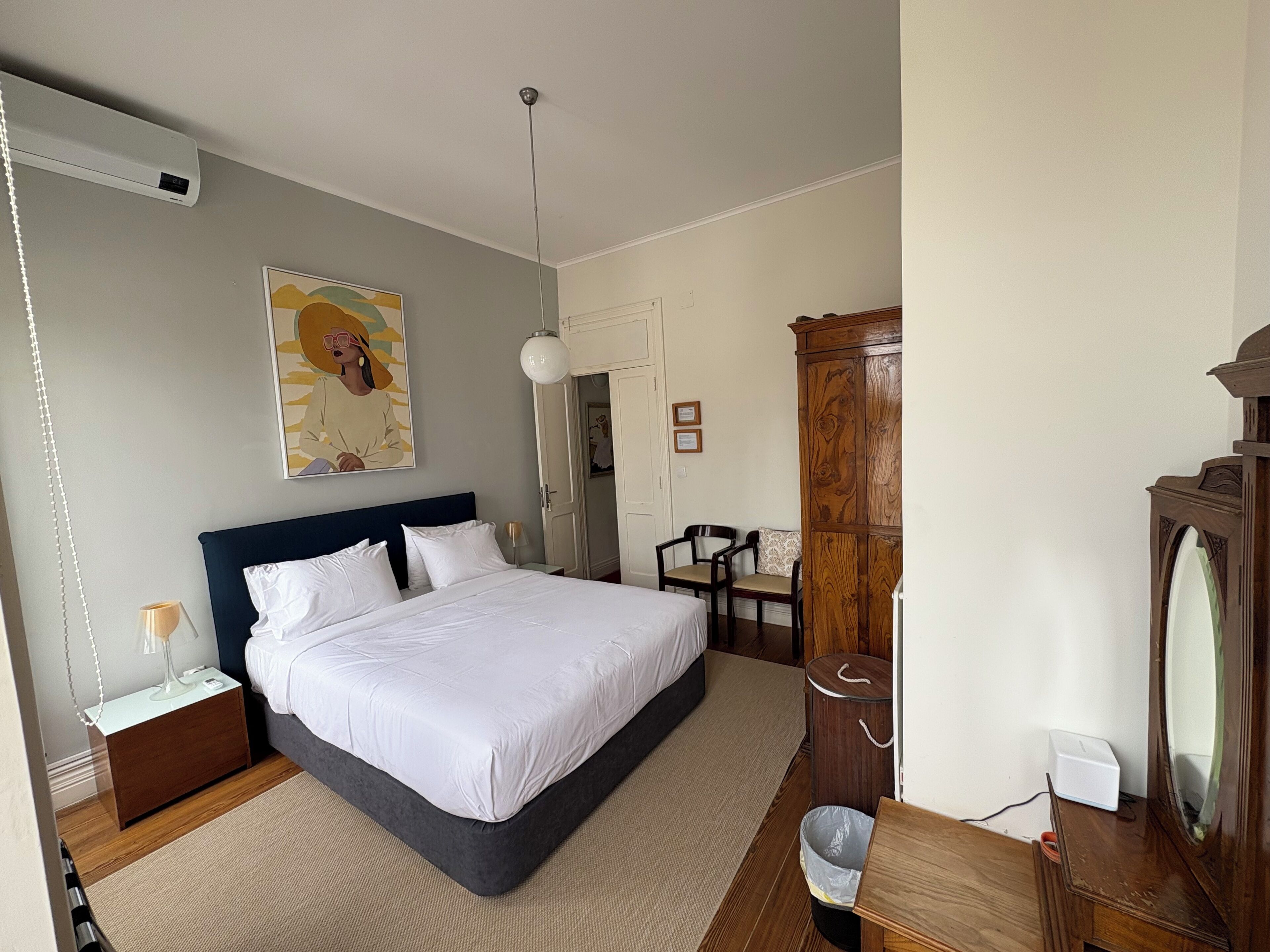 Ein Schlafzimmer mit einem großen Bett, Nachttischen, einem Kleiderschrank, einem Schreibtisch und einem Stuhl.