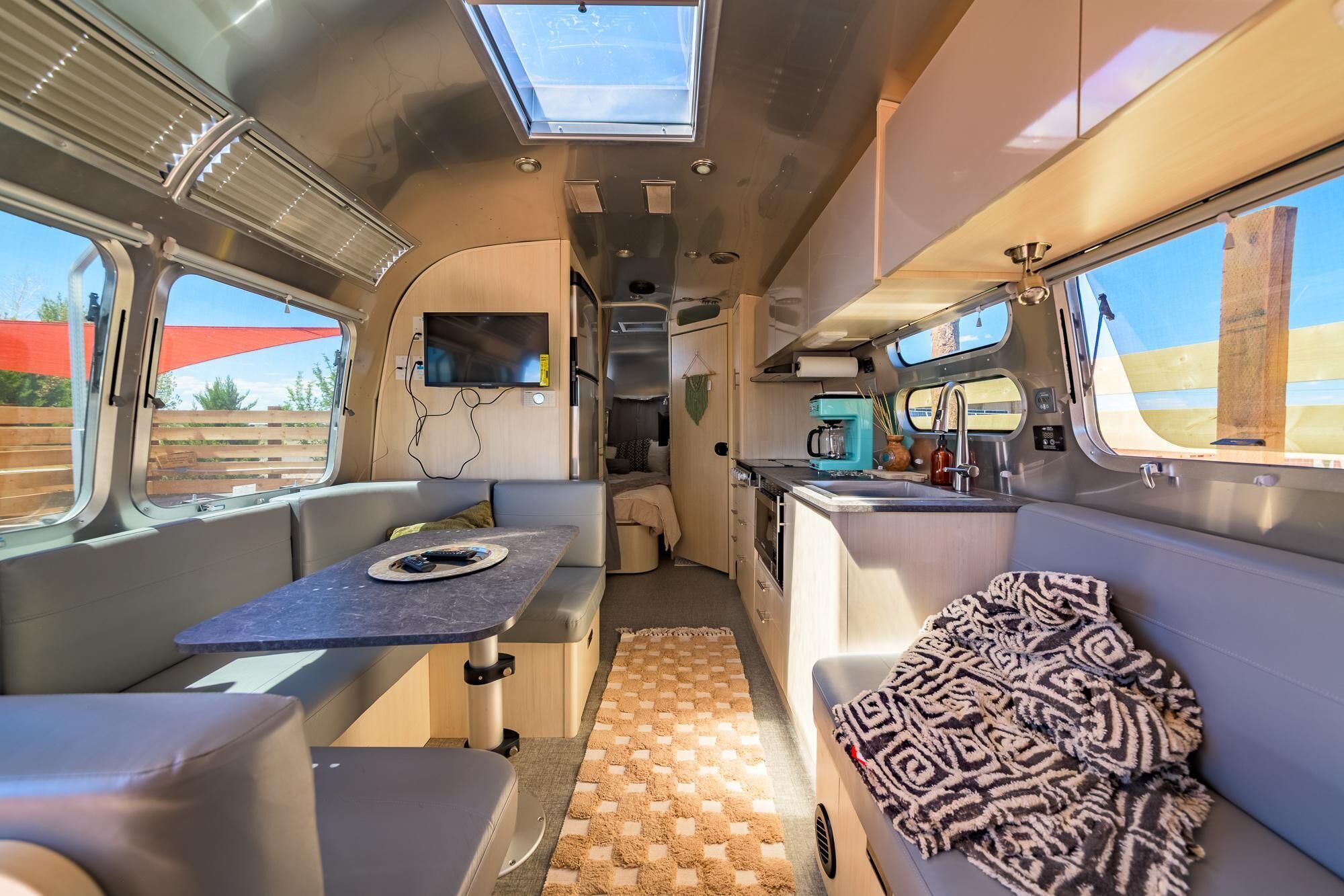 A compact RV interior with a kitchenette, a dining area, and a sleeping space.