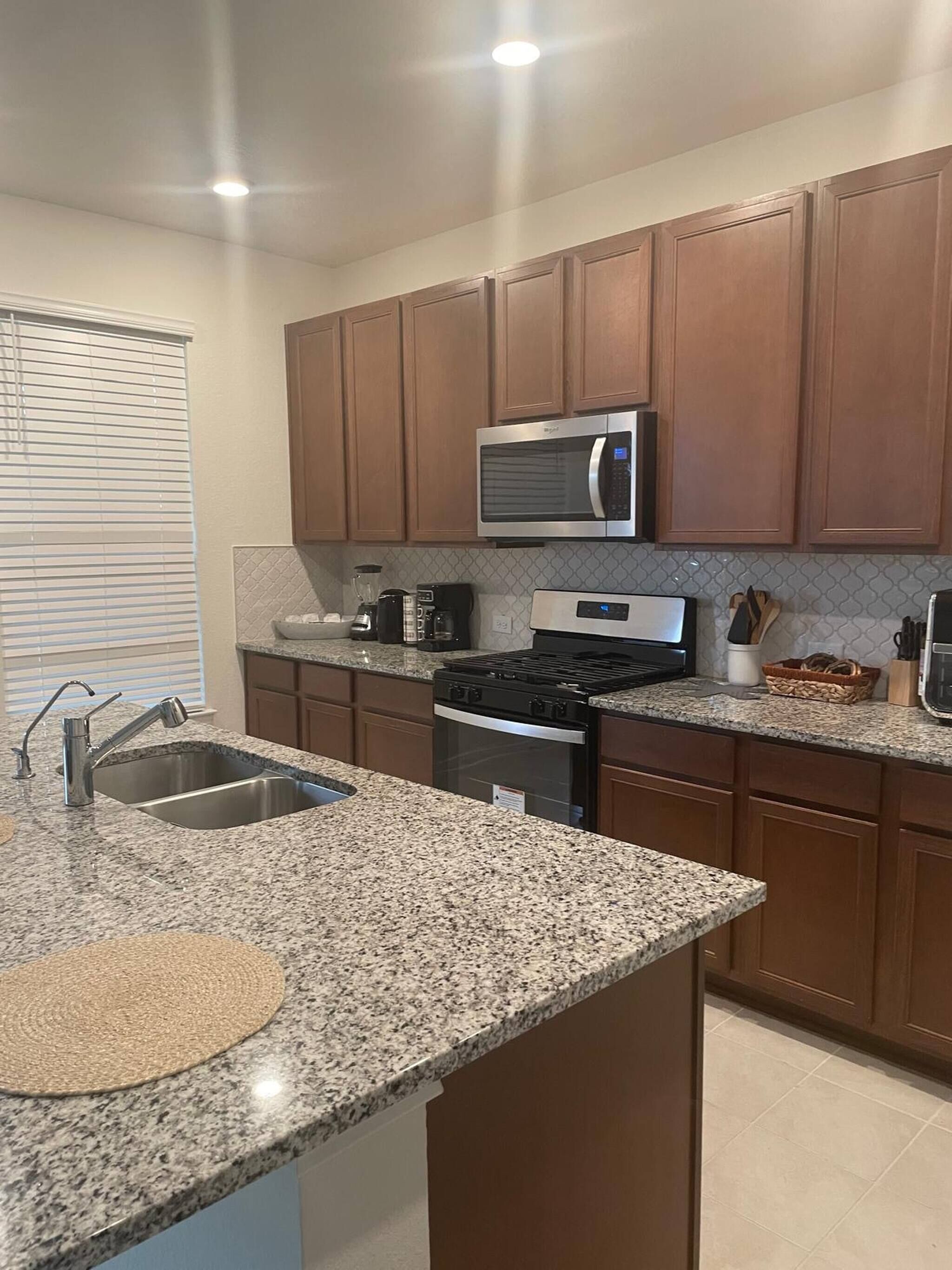 A modern kitchen with granite countertops, stainless steel appliances, and wooden cabinets.
