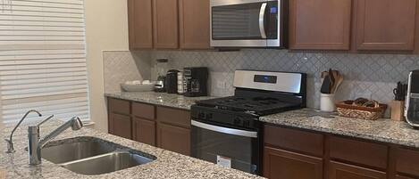 A modern kitchen with granite countertops, stainless steel appliances, and wooden cabinets.