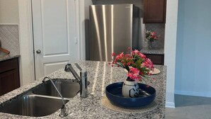 Cocina con encimeras de granito, electrodomésticos de acero inoxidable y armarios de madera.
