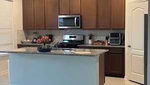 Una cocina moderna con armarios de madera, electrodomésticos de acero inoxidable y encimera de granito.