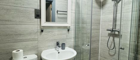 A bathroom with a toilet, sink, and glass-enclosed shower.