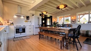 Una cocina con armarios blancos, una mesa de comedor de madera y una lámpara colgante.