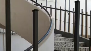 Un escalier en colimaçon avec des marches décorées et une rampe en métal.