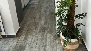 Un couloir étroit avec une plante en pot, un chauffe-eau et, au fond, un coin cuisine.