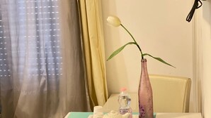 Een kamer met een gedekte tafel voor thee, een vaas met een enkele bloem en een fles water.