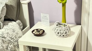 Een witte tafel met een schaal stenen en een decoratieve glazen vaas.