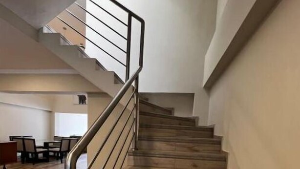 Una scala con gradini in legno e ringhiera in metallo, che conduce a un piano superiore.