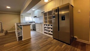 Una cucina moderna con pavimento in legno, mobili bianchi e frigorifero in acciaio inossidabile.