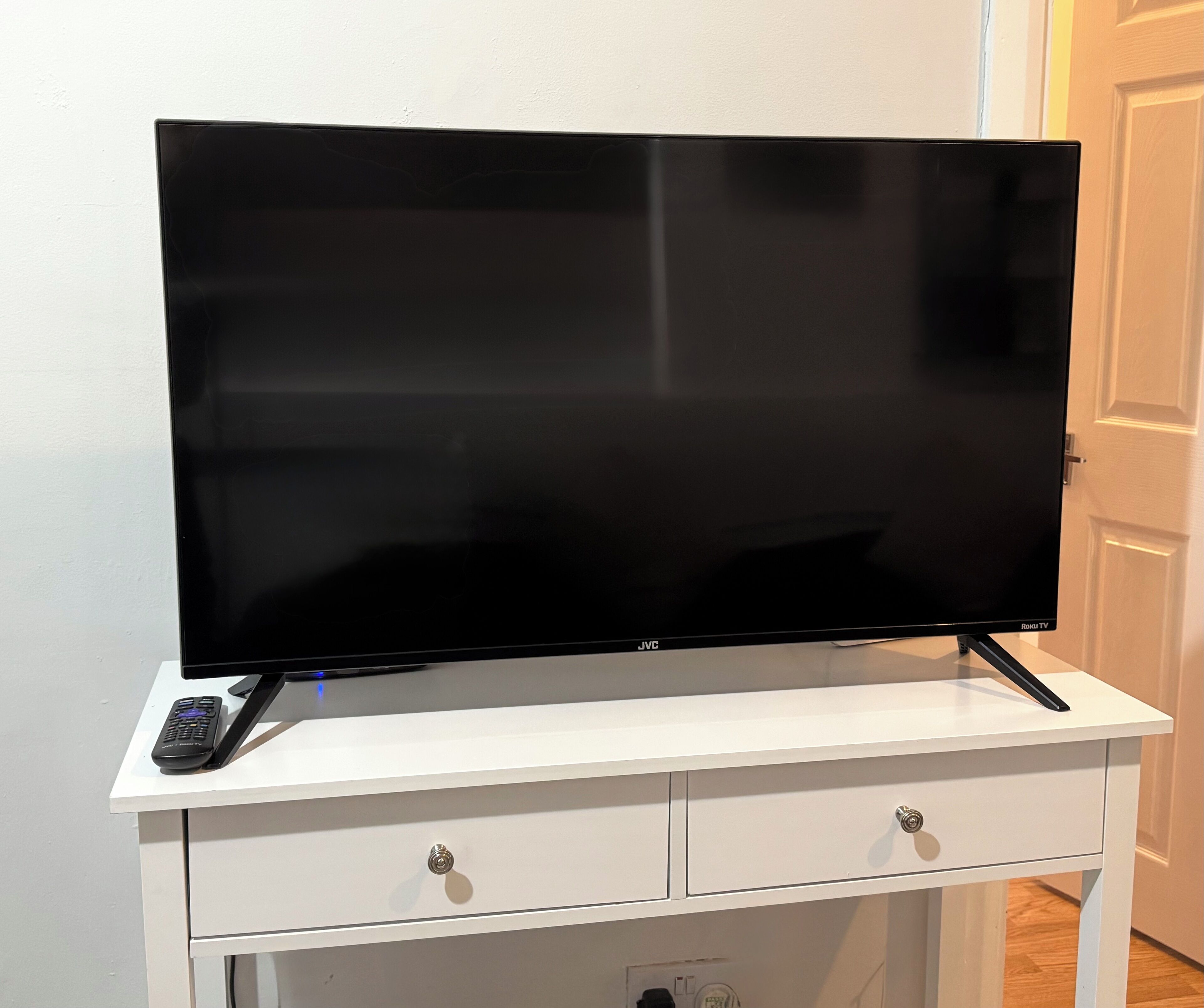 A flat-screen TV on a white TV stand with two drawers.