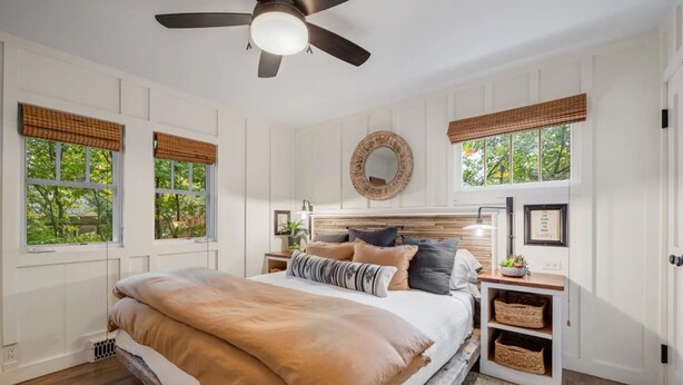 A bedroom with a large bed, a ceiling fan, and a fireplace.