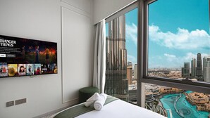 A hotel room with a large window offering a view of a city skyline and a pool.