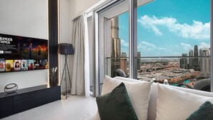 A modern hotel room with a large window offering a city view, a flat-screen TV mounted on the wall, and a minimalist decor.