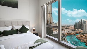 Ein modernes Hotelzimmer mit einem großen Bett, einem Nachttisch und Blick auf Stadt und Wasser.