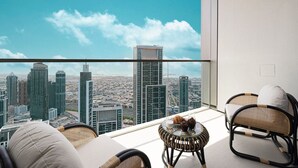 A balcony with a city view, wicker furniture, and a glass table with pastries.