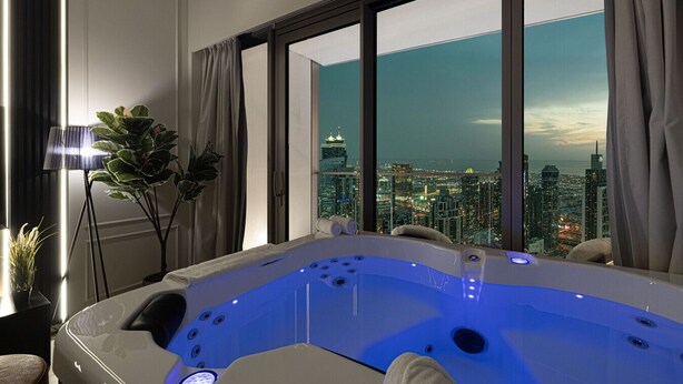 A modern bathroom with a large bathtub, a view of a cityscape, and a floor lamp.