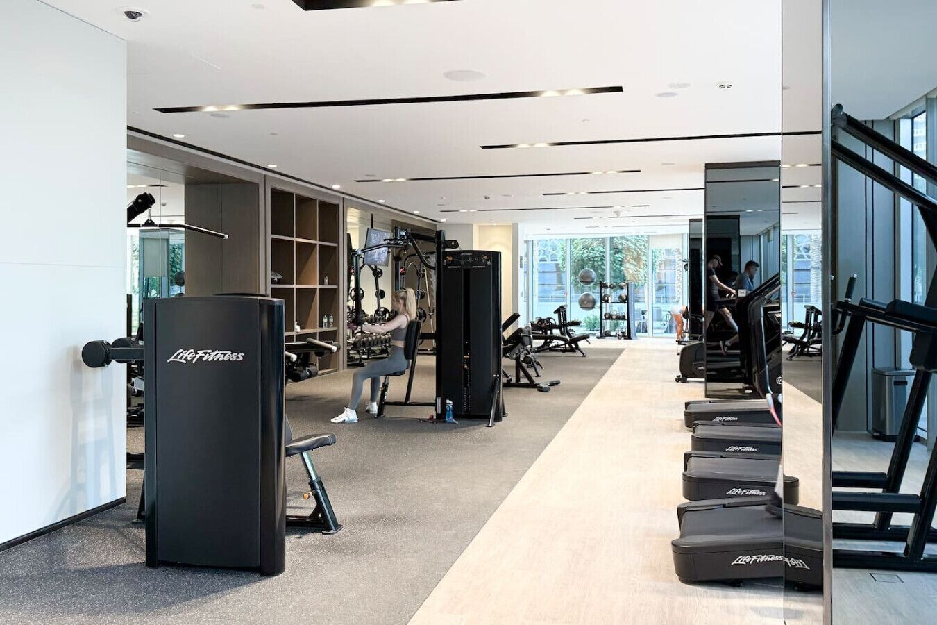 A gym with cardio equipment, weight machines, and a mirrored wall.