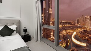 Une chambre d’hôtel moderne dotée d’une grande fenêtre donnant sur le paysage urbain illuminé la nuit.