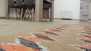 Un comedor con una mesa y sillas, un televisor montado en la pared y una alfombra estampada en el suelo.