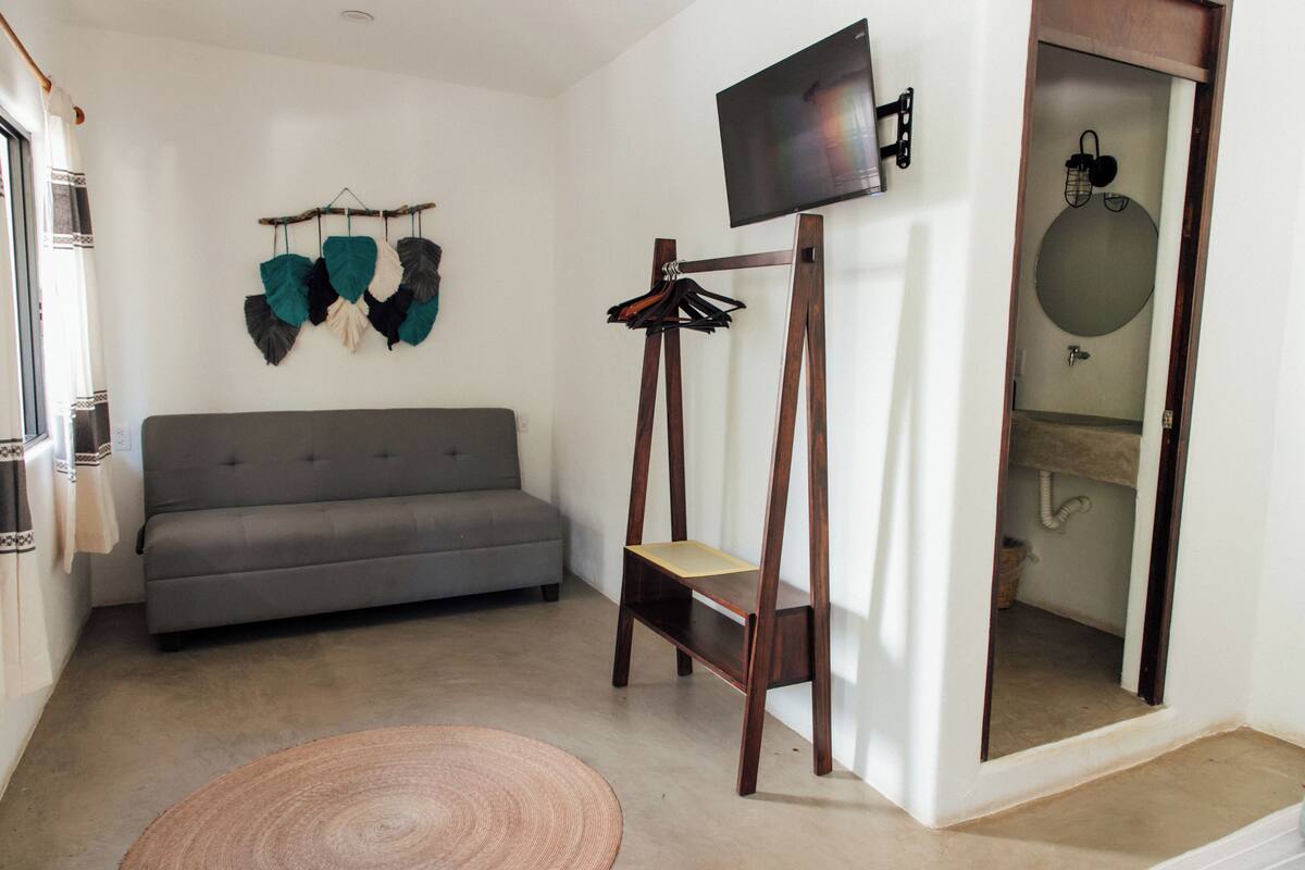 Una sala moderna con un sofá gris, un mueble de televisión de madera y una alfombra redonda.