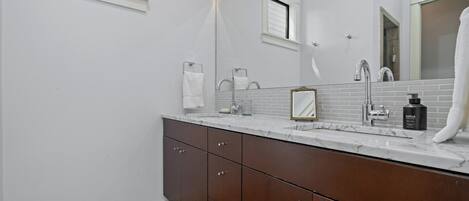 A bathroom with a white vanity, a large mirror, and a window.