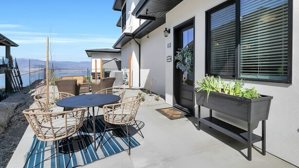Un patio moderno con una mesa y sillas, una jardinera con plantas y vista al océano.
