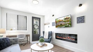 Una sala de estar moderna con chimenea, un sofá, una mesa de centro y un televisor montado en la pared.