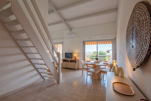 A modern interior with a staircase, a dining area, and a large window offering a view. - Appartement Rayol-Évasion vue mer - Welkeys (Rayol-Canadel-sur-Mer)