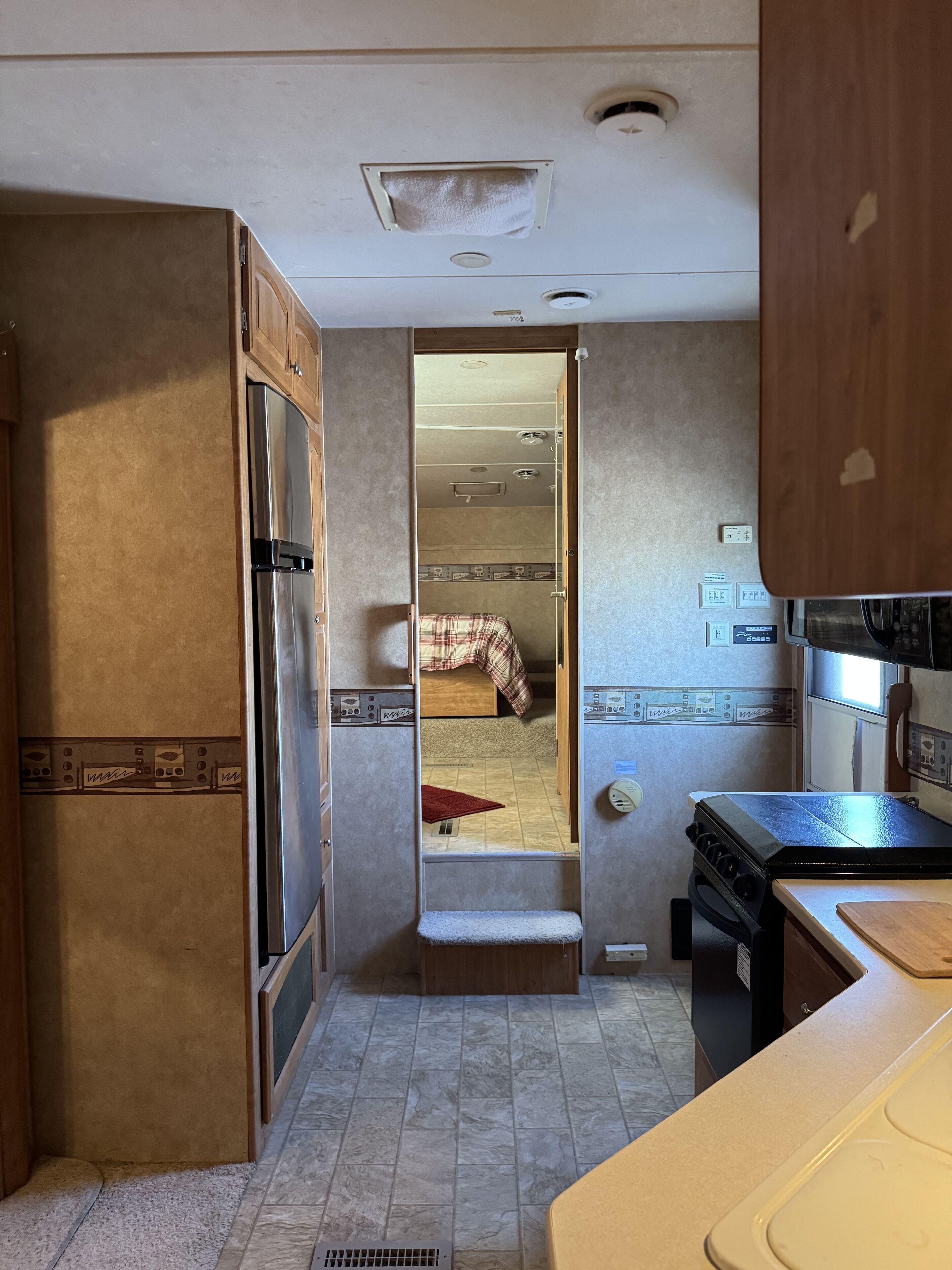 A compact kitchen with a refrigerator, stove, and a small dining area.