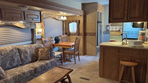 A compact RV interior with a kitchenette, dining area, and a sofa. - Cozy 1-bedroom Rv with pool,WiFi, AC in pleasant Elephant Butte (Elephant Butte)