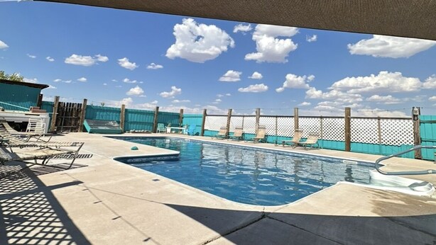 A pool area with a view of the sky, a pool, and lounge chairs. - Cozy 1-bedroom Rv with pool,WiFi, AC in pleasant Elephant Butte (Elephant Butte)