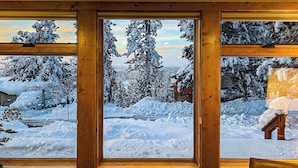 A room with large windows offering a snowy landscape view.