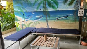 A room with a mural of a beach scene, a bench, and a small table.