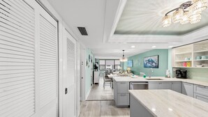 A modern kitchen with a marble countertop, a central island, and a dining area with a table and chairs.
