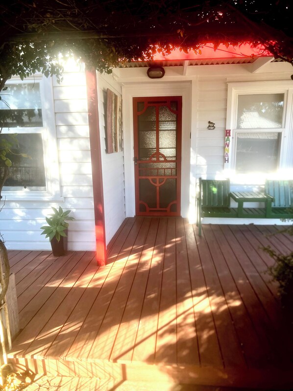 A wooden deck with a red door, a small potted plant, and a bench. - Hill Cottage, comfortable pet friendly home away from home (Clare)