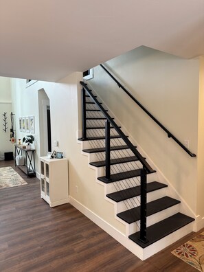 A staircase with black railings and white walls. - Cranberry Lodge | Hot Tub | Gaming Tables | Pets | Sleeping Bear Dunes (Glen Arbor)