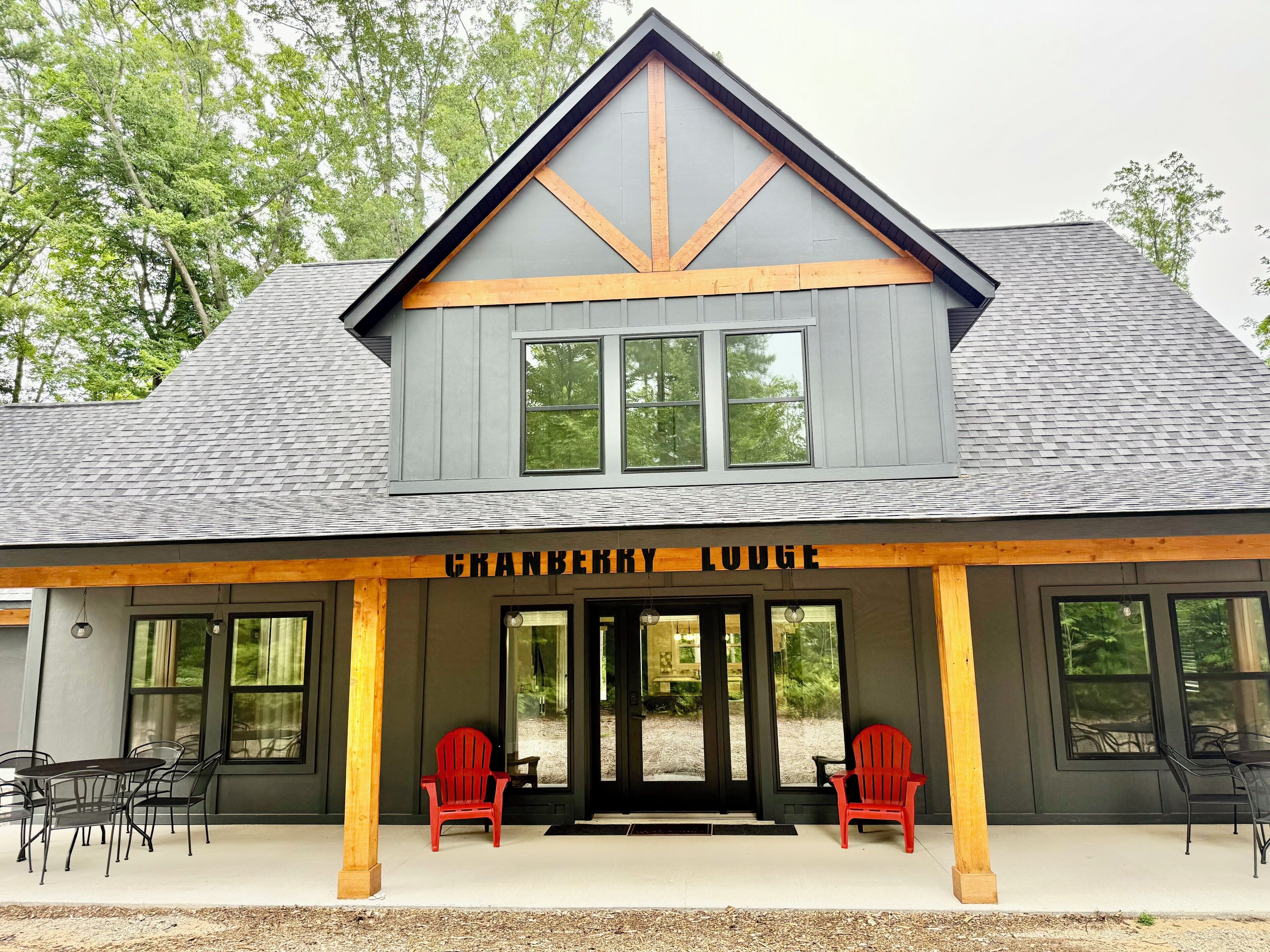 A building with a grey roof, a wooden front porch, and two red chairs.